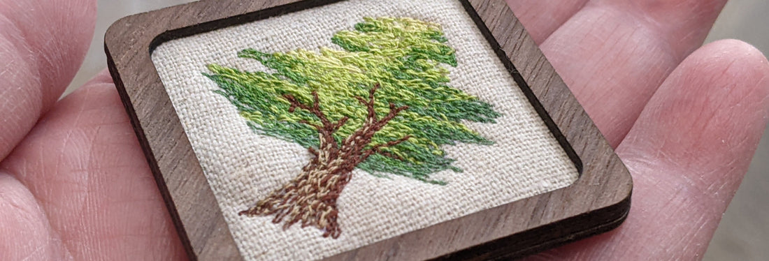 A small thread painted tree held in a person's hand